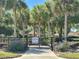 Community entrance gate featuring lush landscaping, mature trees, and a 'private' sign at 728 Ramirez Ave, The Villages, FL 32159