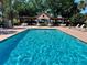 Serene community pool with crystal clear water, shaded seating, and a lush tropical landscape at 728 Ramirez Ave, The Villages, FL 32159