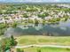 Aerial view showcasing the tranquil lake with golf course and a neighborhood with well-maintained homes at 8043 Pine Hollow Dr, Mount Dora, FL 32757