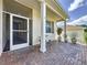 Covered front porch with brick flooring, white columns, and multiple potted plants at 860 Wolf Creek St, Clermont, FL 34711