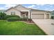 Charming home featuring a well-manicured lawn, mature landscaping, and a two-car garage at 879 Lucky Ln, The Villages, FL 32162
