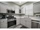 White kitchen with stainless steel appliances including range, microwave, dishwasher and sink with bright natural light at 879 Lucky Ln, The Villages, FL 32162
