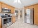 Well-equipped kitchen featuring stainless steel appliances, wood cabinetry, and an open layout to the living spaces at 1061 Soledad Way, The Villages, FL 32159