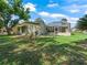 Backyard view showcasing the house with a screened-in patio and lush green lawn at 1105 Del Toro Dr, The Villages, FL 32159