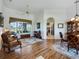Cozy living room featuring beautiful wood floors and large windows with views of the golf course at 11702 Se 173Rd Lane Rd, Summerfield, FL 34491