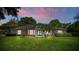 Well-lit home showcasing a beautifully landscaped front yard at dusk, perfect for relaxation at 11811 Ridge View Cir, Clermont, FL 34711