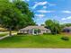 Well-maintained single-story home featuring a lush green lawn, mature trees, and manicured landscaping at 11811 Ridge View Cir, Clermont, FL 34711