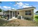 Exterior view of the home showcasing a screened lanai and a well-maintained backyard with landscaping at 1203 Zapata Pl, The Villages, FL 32159