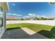 Large backyard featuring a concrete patio and a well-maintained lawn enclosed by a pristine white privacy fence at 12054 Ne 51St Cir, Oxford, FL 34484