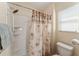 Bathroom with a white shower-tub combination, palm tree shower curtain, and window at 12054 Ne 51St Cir, Oxford, FL 34484