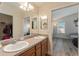 Bathroom featuring a double sink vanity with warm wood cabinets and view into the bedroom at 12054 Ne 51St Cir, Oxford, FL 34484