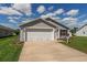 Inviting single-story home featuring a two-car garage, a concrete driveway, and a well-manicured front lawn at 12054 Ne 51St Cir, Oxford, FL 34484