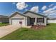 Charming single-story home with a two-car garage, landscaped front yard, and neighborhood sign at 12054 Ne 51St Cir, Oxford, FL 34484