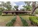 Charming single-story brick home with a well-manicured lawn, mature trees, and a inviting walkway at 12196 Ne 4Th Pl, Oxford, FL 34484
