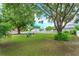 Picture of a large backyard with green lawn, mature shade trees, and seating area with chairs at 12846 Brown Bark Trl, Clermont, FL 34711