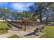 Community playground with climbing structures, slides, and swings, enclosed by a black chain link fence at 12846 Brown Bark Trl, Clermont, FL 34711
