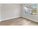 Bright, minimalist bedroom with wood-look floors and a large window at 13524 Sw 89 St, Dunnellon, FL 34432