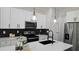 Modern kitchen featuring white cabinets, stainless steel appliances, a kitchen island with a black faucet, and pendant lighting at 13524 Sw 89 St, Dunnellon, FL 34432