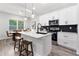 Open-concept kitchen featuring white cabinets, stainless appliances, an island with seating, and a dining area with natural light at 13524 Sw 89 St, Dunnellon, FL 34432
