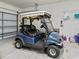 Garage view featuring a blue golf cart with comfortable seats, side mirrors, and overhead storage at 14235 Se 85Th Ave, Summerfield, FL 34491