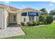 Close-up of the front exterior, showcasing the well-maintained landscaping and screened-in porch at 1501 Lavaca Ln, The Villages, FL 32159