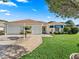 Charming home featuring a two-car garage, manicured lawn, and mature landscaping at 1501 Lavaca Ln, The Villages, FL 32159