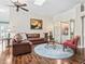 Cozy living room featuring hardwood floors, leather furniture, a round rug, and a decorative cabinet at 1501 Lavaca Ln, The Villages, FL 32159
