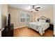 Cozy bedroom features a ceiling fan, wood floors, and a window with plantation shutters at 1502 Blueberry Way, The Villages, FL 32162