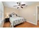 Cozy bedroom features a ceiling fan, wood floors, and a window with plantation shutters at 1502 Blueberry Way, The Villages, FL 32162