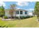 A charming white home is surrounded by well-maintained landscaping and a lush green lawn at 1502 Blueberry Way, The Villages, FL 32162