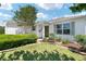 Front exterior featuring a well-kept lawn, mature landscaping, and charming curb appeal at 1502 Blueberry Way, The Villages, FL 32162
