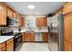 Bright kitchen featuring stainless steel appliances, granite countertops, and wooden cabinetry at 1502 Blueberry Way, The Villages, FL 32162
