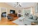 Cozy living room featuring wood floors, TV, stylish seating, and access to a sunlit outdoor area at 1502 Blueberry Way, The Villages, FL 32162