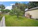 Grassy backyard with lush lawn, fruit trees, arched trellis, and partial view of the house at 1512 S Pointe Dr, Leesburg, FL 34748