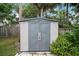 Outdoor storage shed surrounded by greenery, providing practical storage in the fenced yard at 1512 S Pointe Dr, Leesburg, FL 34748