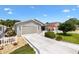 Inviting single-story home featuring a well-manicured lawn, a white picket fence, and an attached garage at 1513 Lozano Ave, The Villages, FL 32159