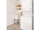Bright laundry room features a stacked washer/dryer, utility sink, and open shelving for storage at 1513 Lozano Ave, The Villages, FL 32159