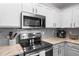 Close up of modern kitchen featuring granite countertops, stainless steel appliances, white cabinets, and gray subway tile at 15501 Markham Dr, Clermont, FL 34714
