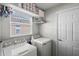 Bright laundry room with modern appliances, storage shelves, and a window for natural light at 15501 Markham Dr, Clermont, FL 34714