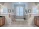 Bright bathroom featuring a tiled tub with window shutters and double vanity sinks at 1573 Blenheim Trl, The Villages, FL 32162