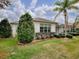 Beautifully landscaped home exterior with a lush lawn and mature trees and a screened in lanai at 1573 Blenheim Trl, The Villages, FL 32162
