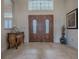 Inviting foyer with decorative table, tile flooring and beautiful wood double doors at 1573 Blenheim Trl, The Villages, FL 32162