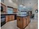 Spacious kitchen with black appliances, granite countertops, central island, and lots of wooden cabinets at 1573 Blenheim Trl, The Villages, FL 32162