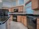 Kitchen featuring black appliances, granite countertops, wood cabinets, decorative back splash and tile flooring at 1573 Blenheim Trl, The Villages, FL 32162