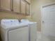 Bright laundry room featuring front load washer and dryer, storage cabinets, and tile floor at 1573 Blenheim Trl, The Villages, FL 32162