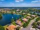 Aerial view of lakeside community with many homes, lush greenery, and a fountain in the lake at 2029 Stefano Ct, Mount Dora, FL 32757