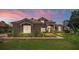 Elegant home with a well-manicured lawn, mature trees, and colorful landscaping at sunset at 2029 Stefano Ct, Mount Dora, FL 32757