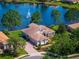 Beautiful lakefront home featuring lush landscaping, tile roof, and brick driveway with a scenic fountain view at 2029 Stefano Ct, Mount Dora, FL 32757