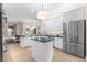 Modern kitchen with white cabinets, blue countertops, an island, stainless appliances, and an open living area at 2029 Stefano Ct, Mount Dora, FL 32757