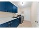 Functional laundry room with modern washer, dryer, blue cabinets, and stainless steel sink provides convenience and style at 2029 Stefano Ct, Mount Dora, FL 32757